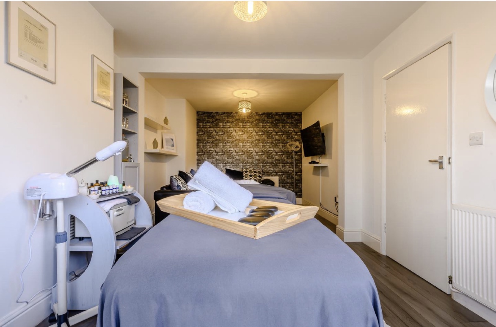 Treatment room at Mind Body And Soul London, bed made up with a blue blanket and folded white towels