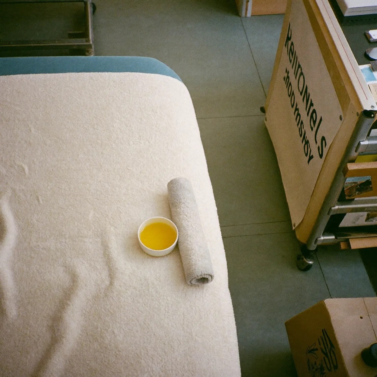 Rolled towel and a bowl of warm oil beside the massage couch